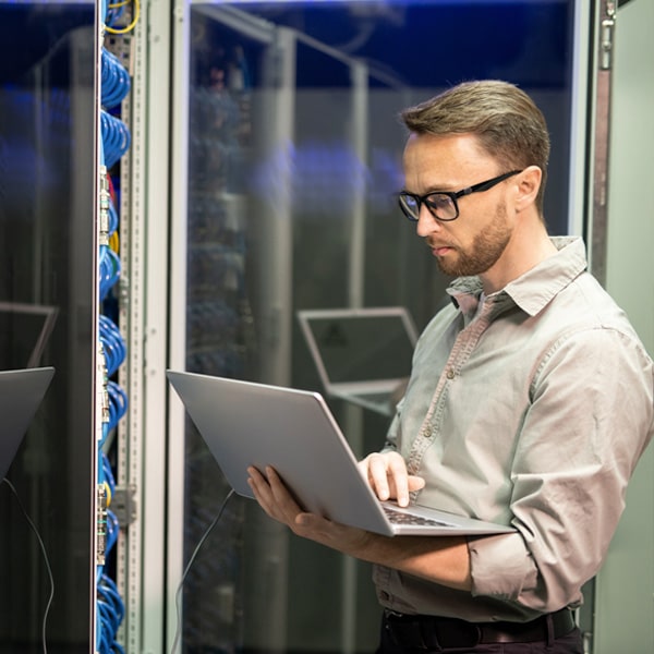 Person in a server room on a laptop.