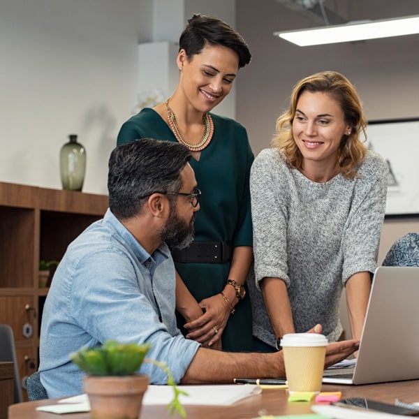 Three people talking around a computer.