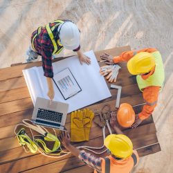 People in hard hats looking at a computer wishing they had IT support for construction companies.